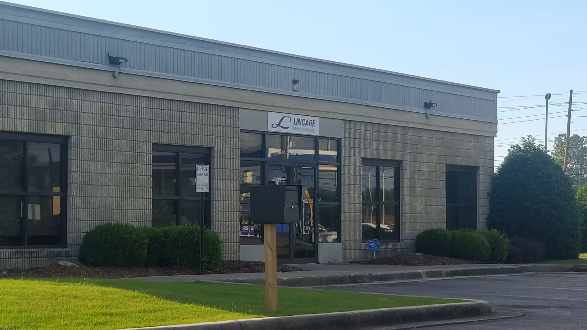 Exterior view of a Lincare facility with glass doors and trimmed shrubs.