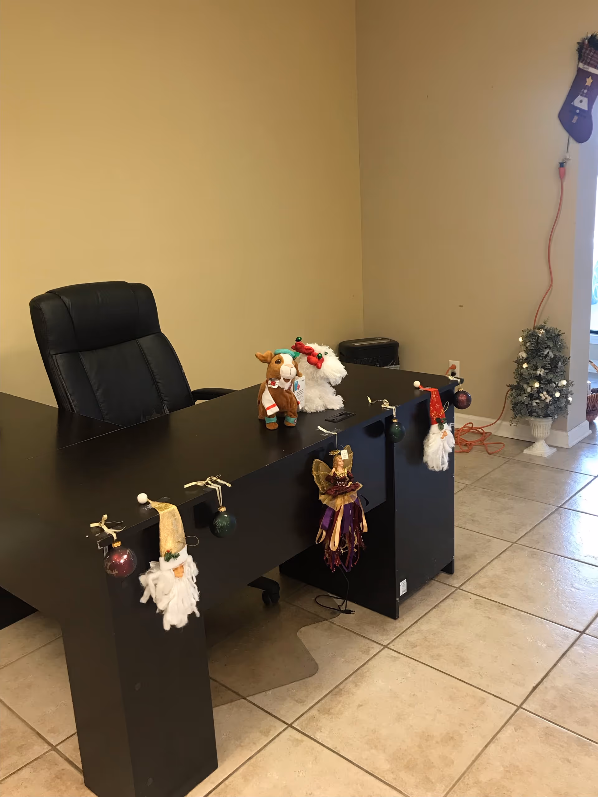 Reception desk decorated with Christmas ornaments and small holiday figures in a facility lobby.