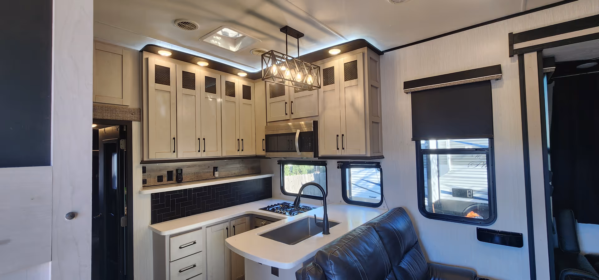 Modern kitchen area with sink, stove, cabinets, and a nearby sofa.
