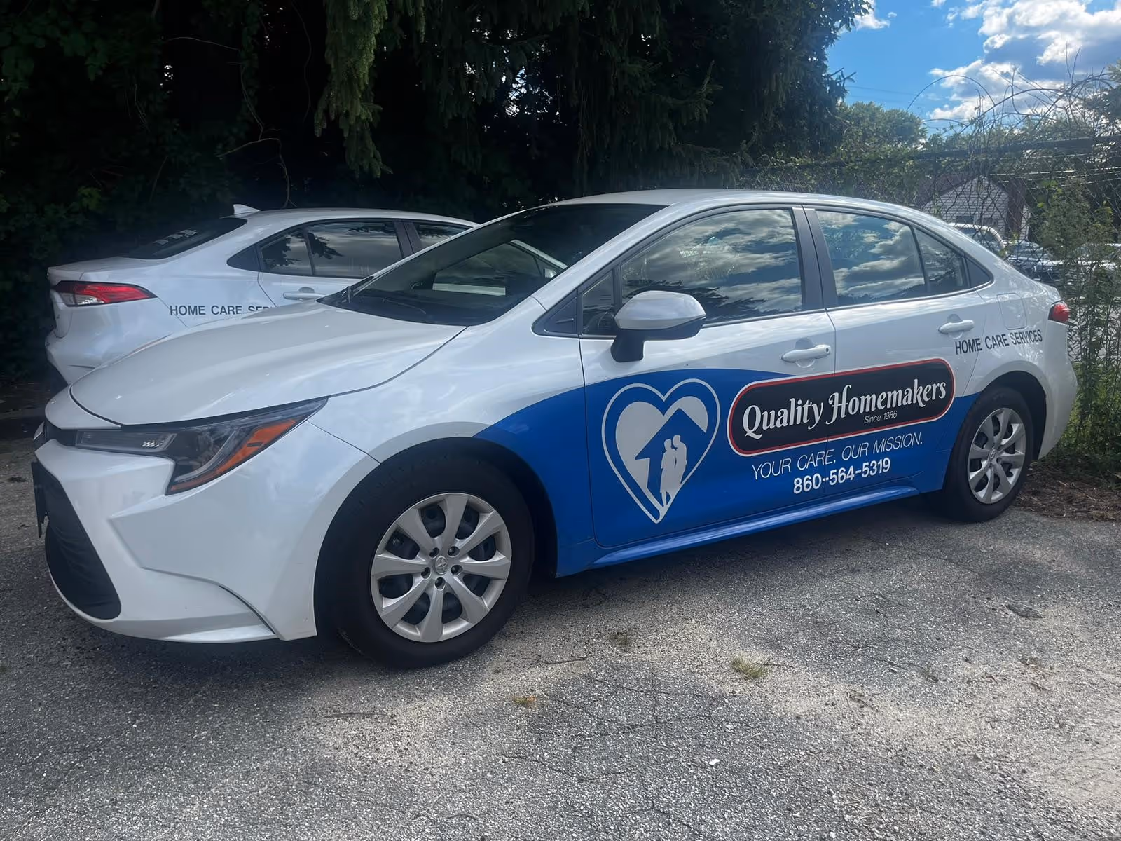 Two white Quality Homemakers service cars parked in a lot outside.