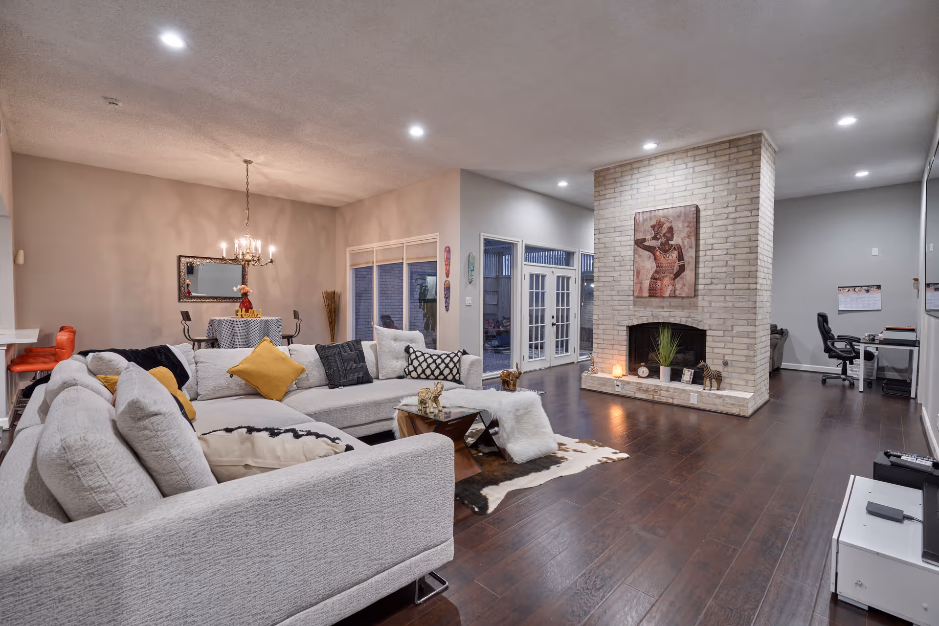 Spacious living area with a gray sectional, fireplace, and dining nook at Nesta's Wellness Retreat.