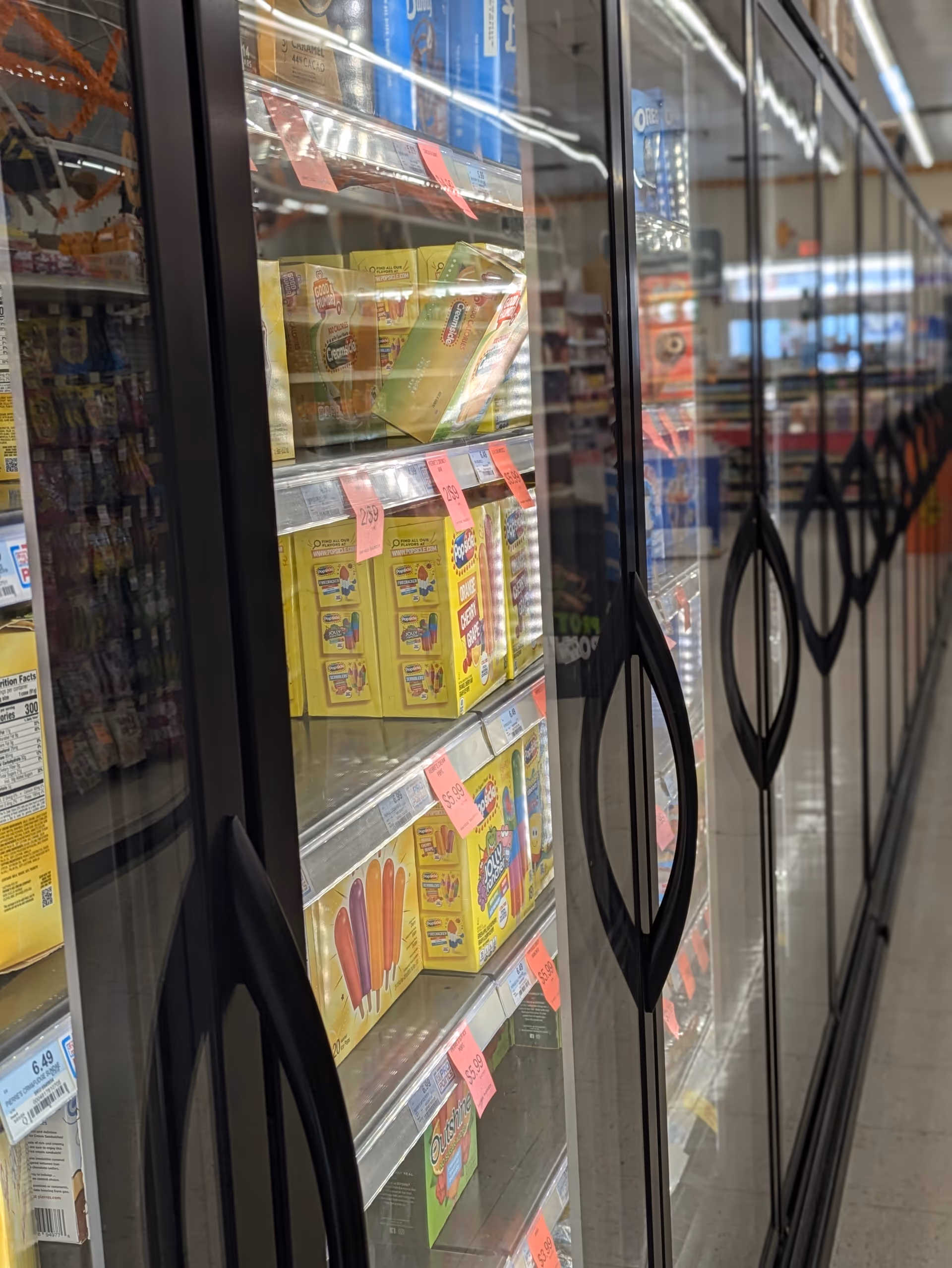 Row of glass-door refrigerated display cases filled with assorted packaged goods.