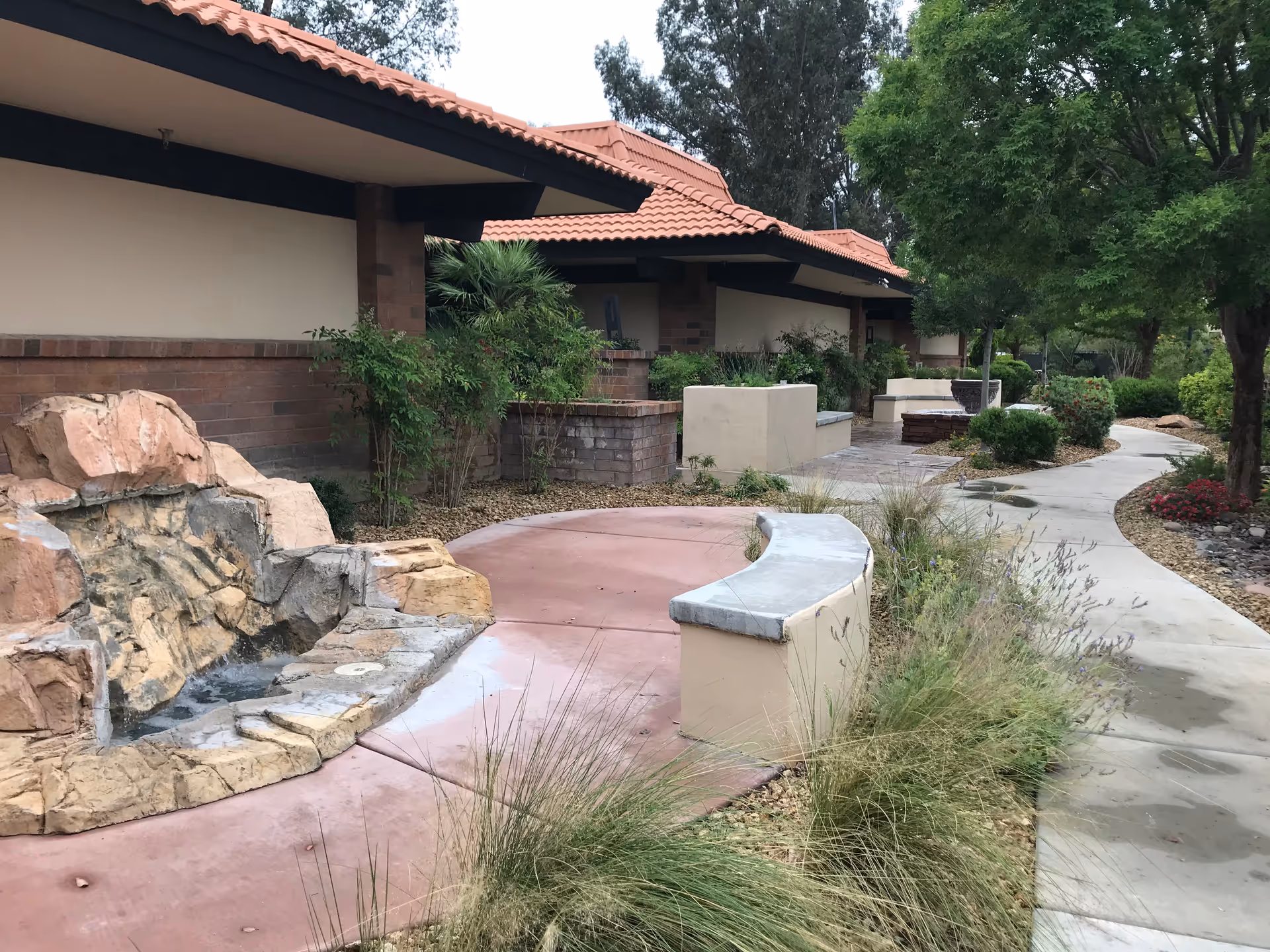 Outdoor courtyard at Nathan Adelson Hospice with benches, trees, and stone features.