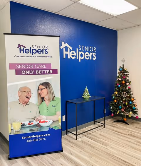 Reception area with blue Senior Helpers wall, banner, and decorated Christmas tree.