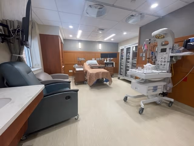 Hospital exam room at Glendive Medical Center with bed, chairs, and medical equipment.