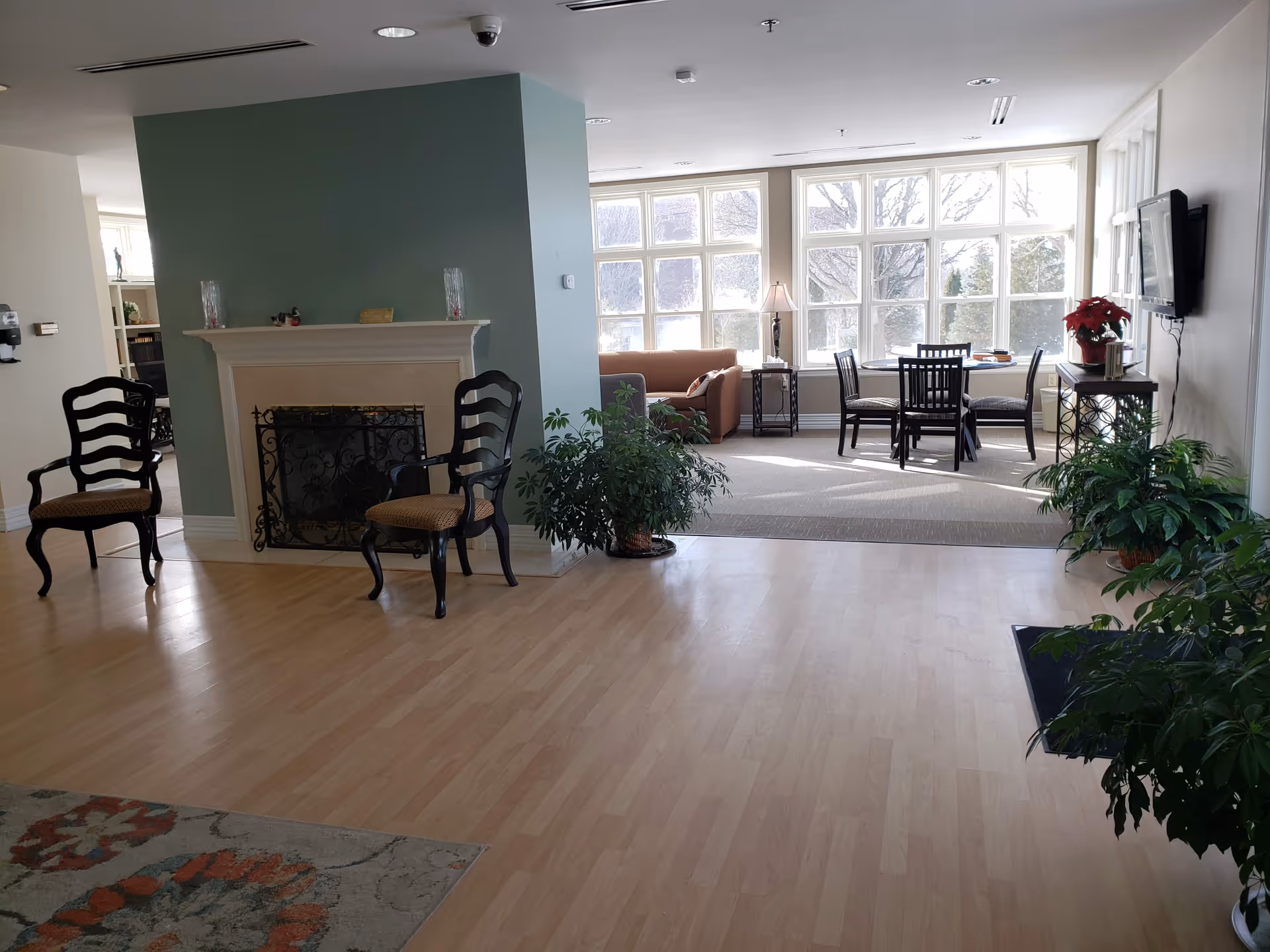 Lounge area of Mercy Hospice with sofa, chairs, windows, and plants.