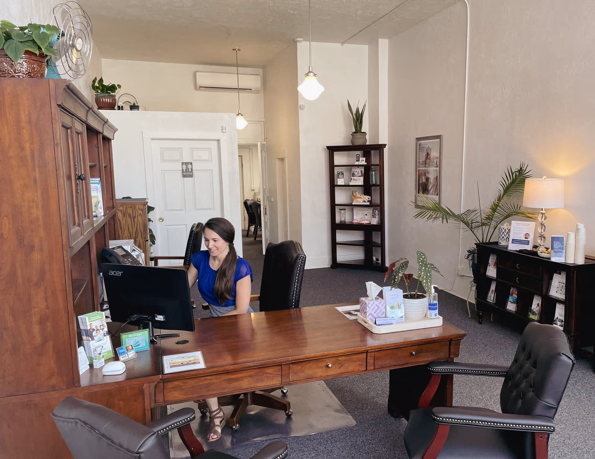 Reception desk with a woman at a computer in a spacious office lobby.