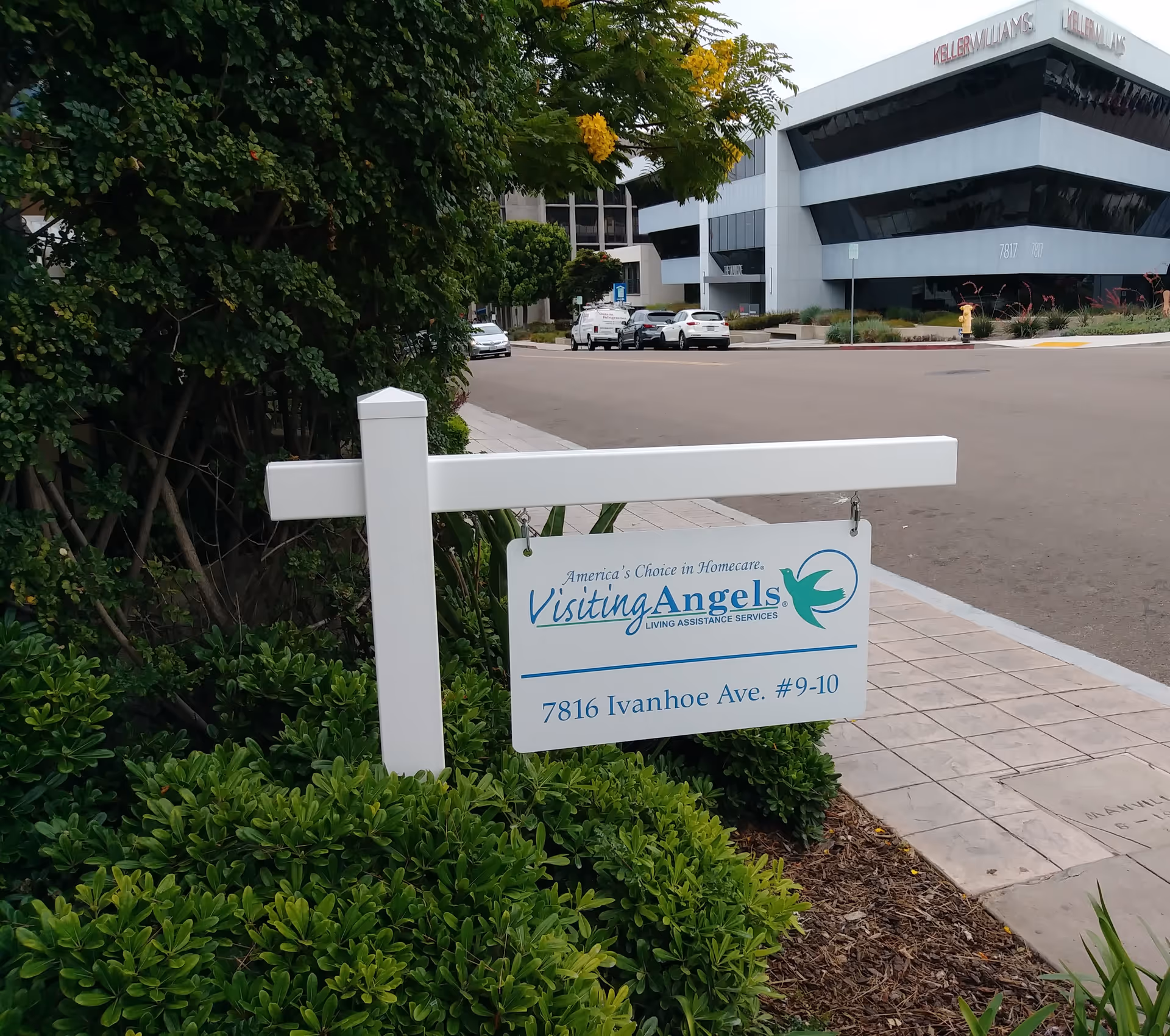 Outdoor sign for Visiting Angels Senior Home Care in front of a modern office building.