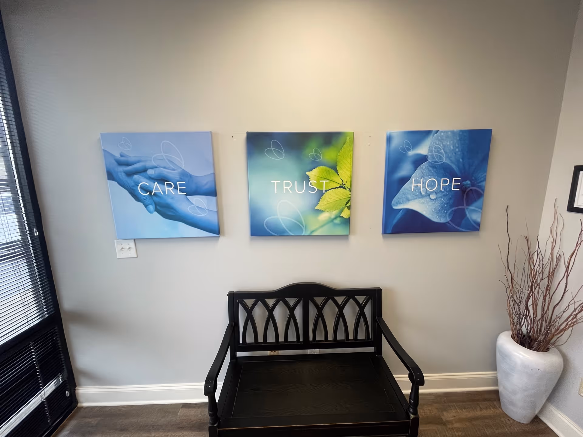 Interior lobby seating with a black bench and three wall art panels reading Care, Trust, Hope.