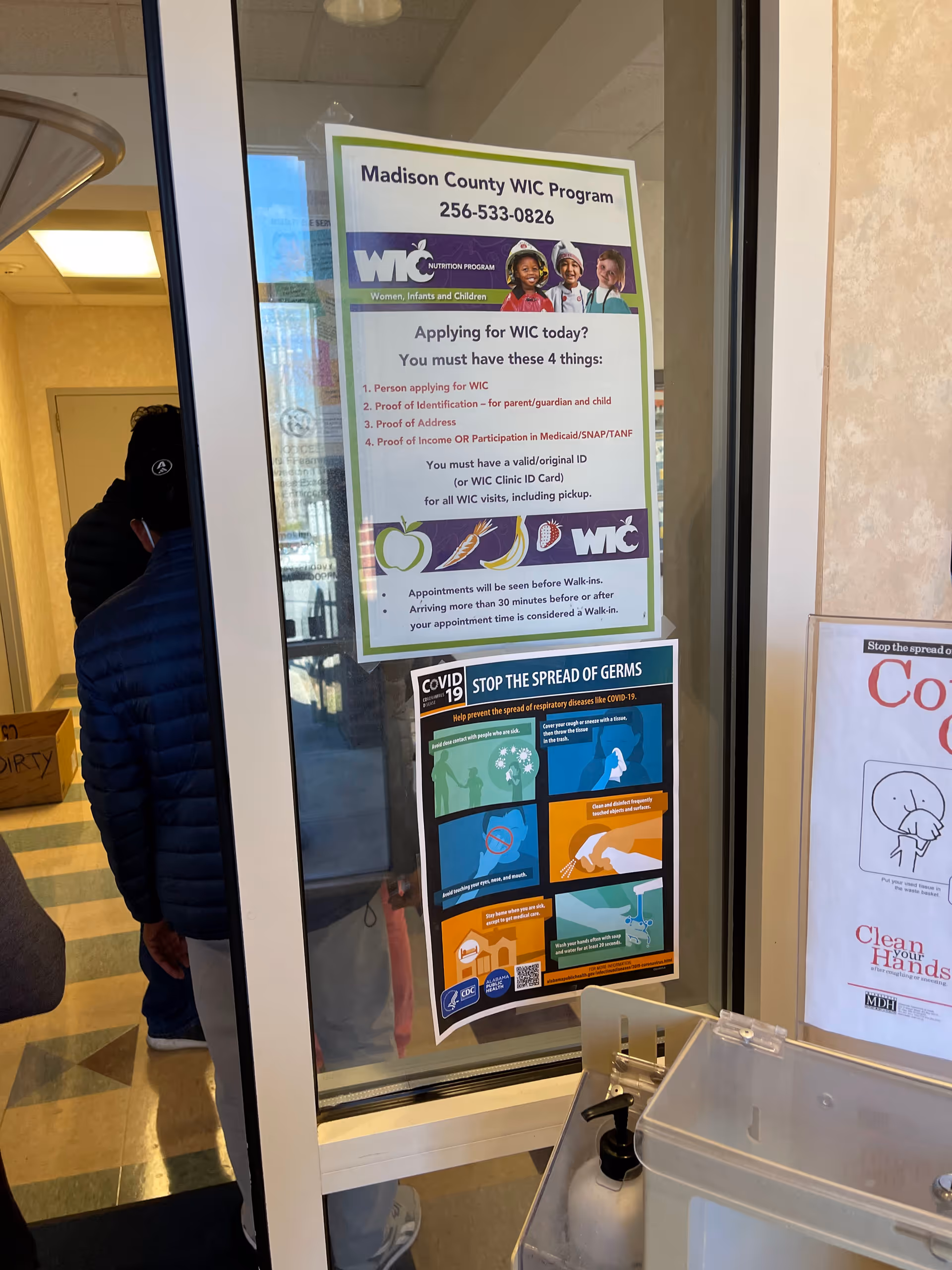 Indoor doorway with health department posters and a germ-prevention flyer visible.