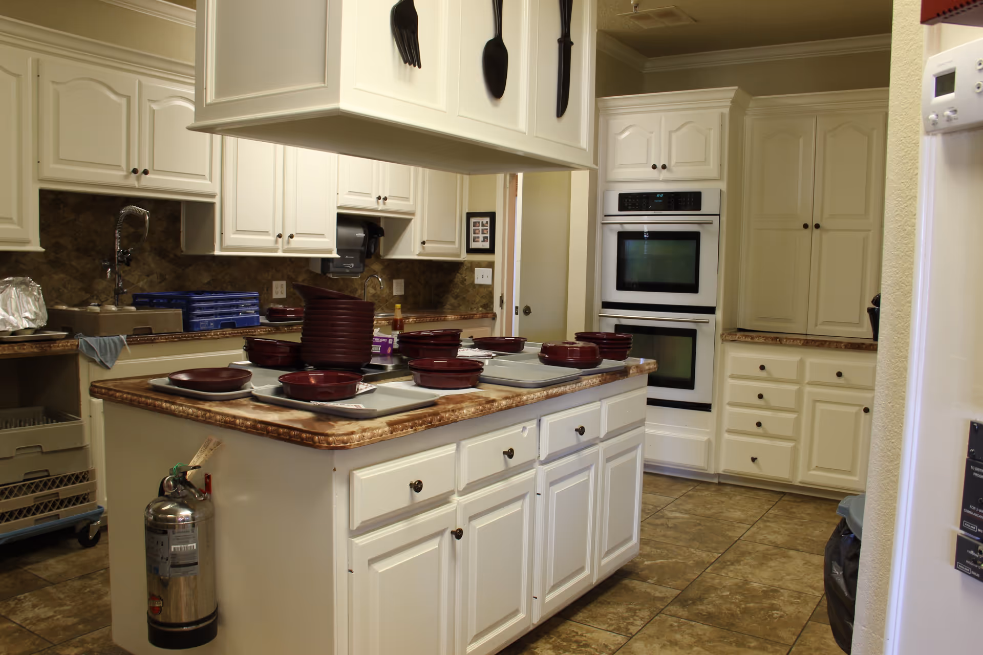 Bright white kitchen with island, cabinets, and built-in ovens in Wilshire on 4th.