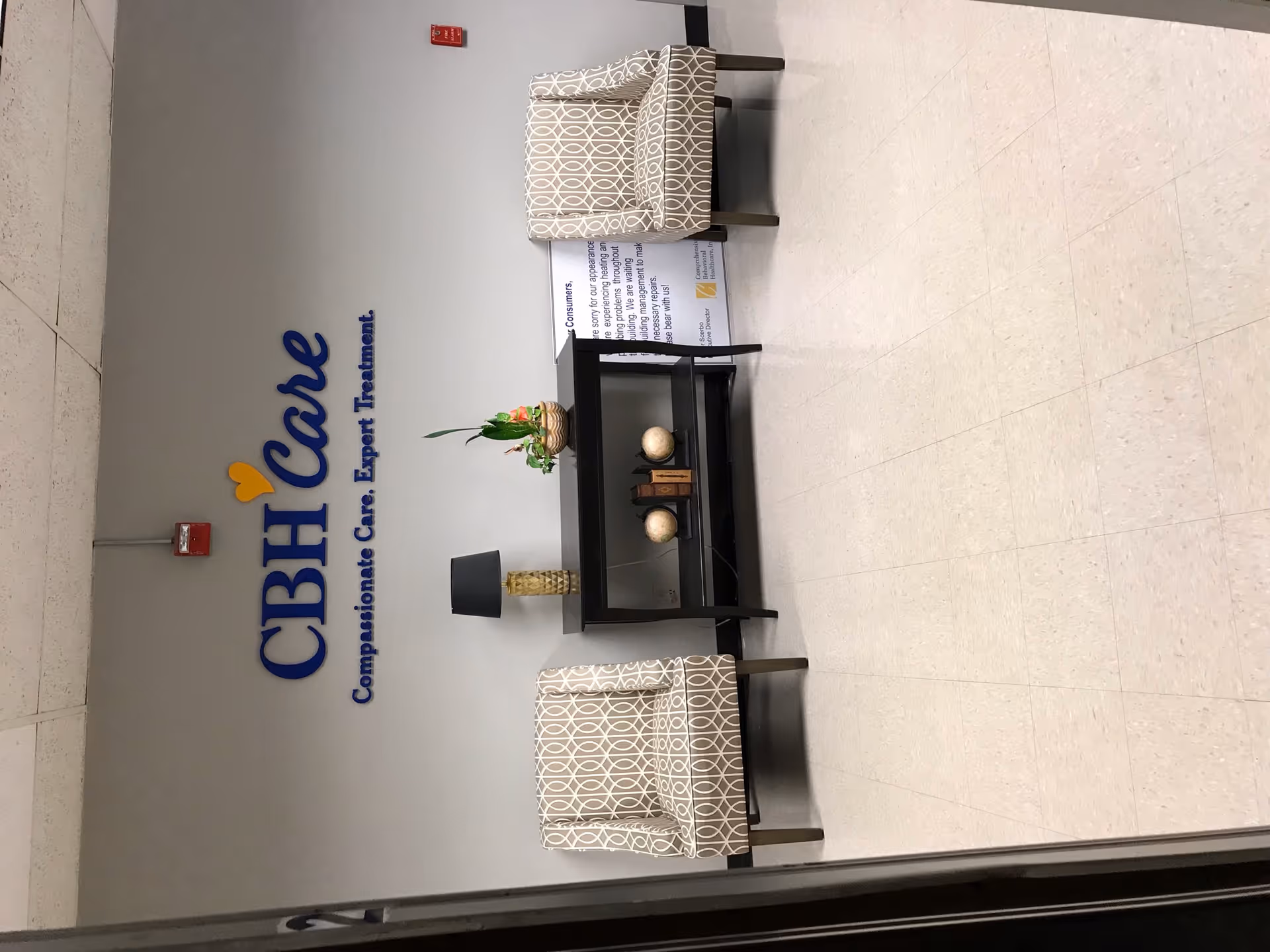 Lobby area with CBH Care sign, two patterned chairs, and a fireplace.