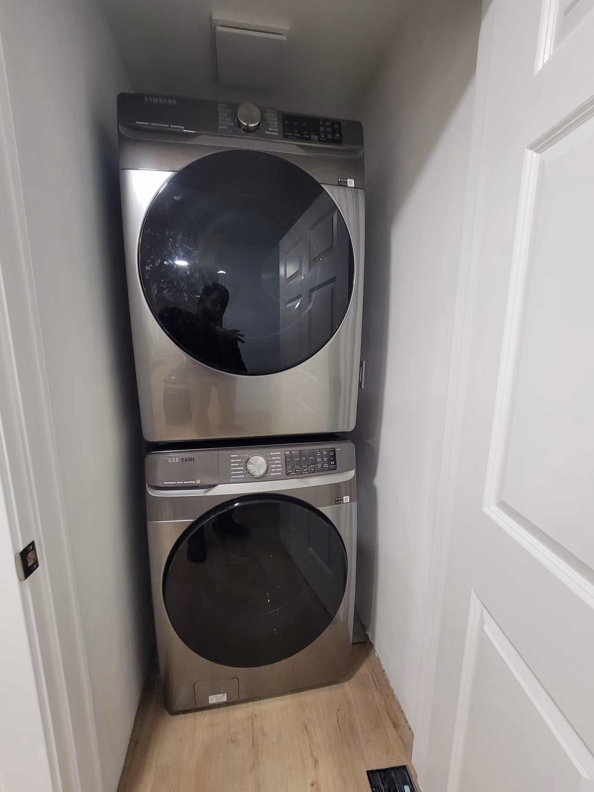 Stacked front-loading washer and dryer in a narrow laundry closet.