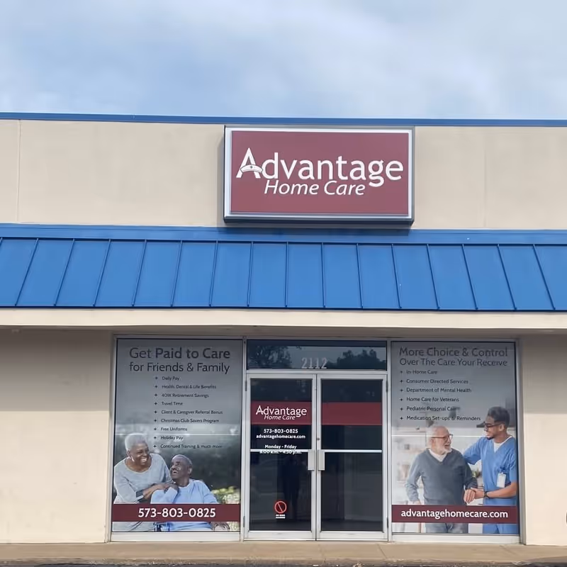 Exterior storefront of Advantage Home Care with a maroon sign and window banners.