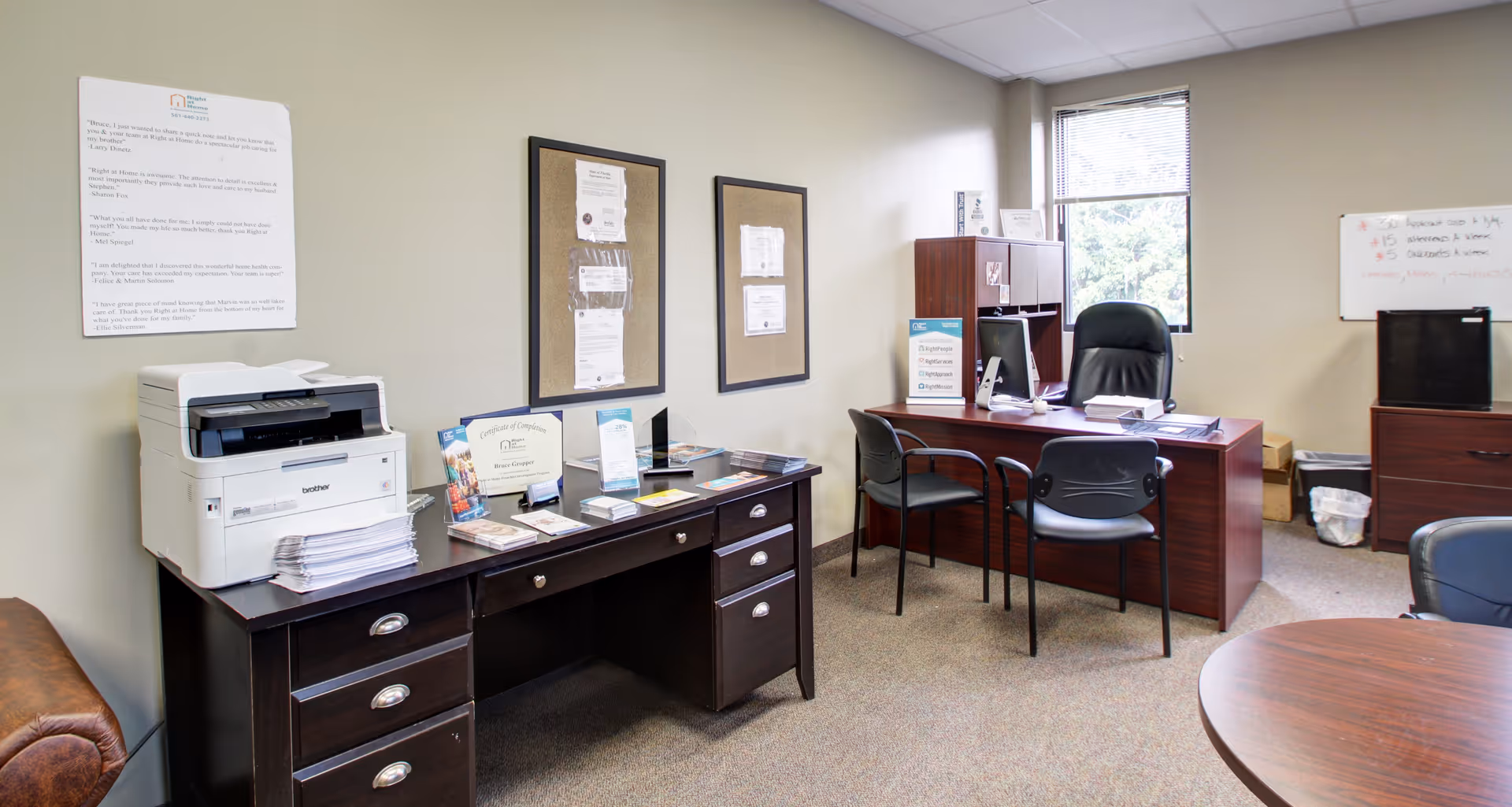 Interior office area in a senior care facility with desks, printer, chairs, and bulletin boards.