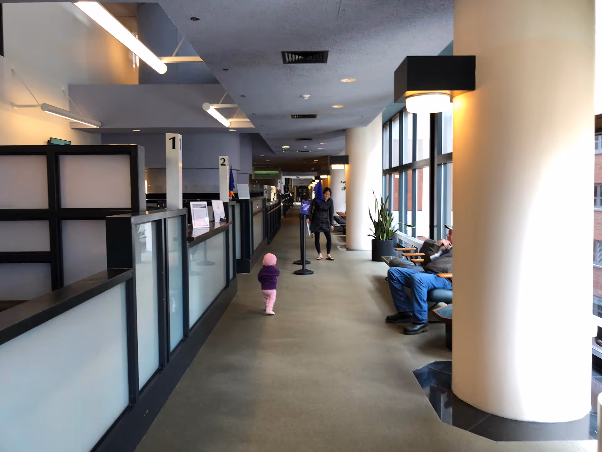 Long Johns Hopkins Outpatient Center hallway with check-in desks, seating, and a walking child.