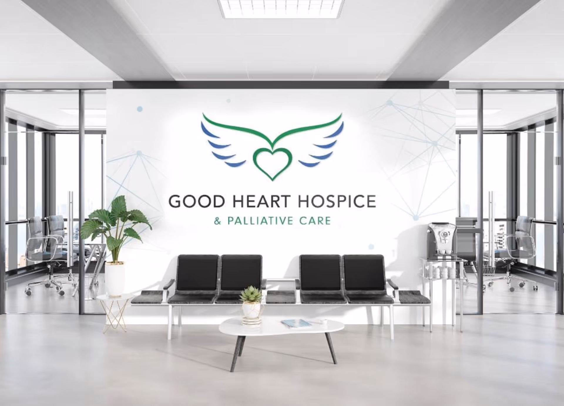 Modern lobby interior with a Good Heart Hospice banner, black seating, plants, and glass walls.