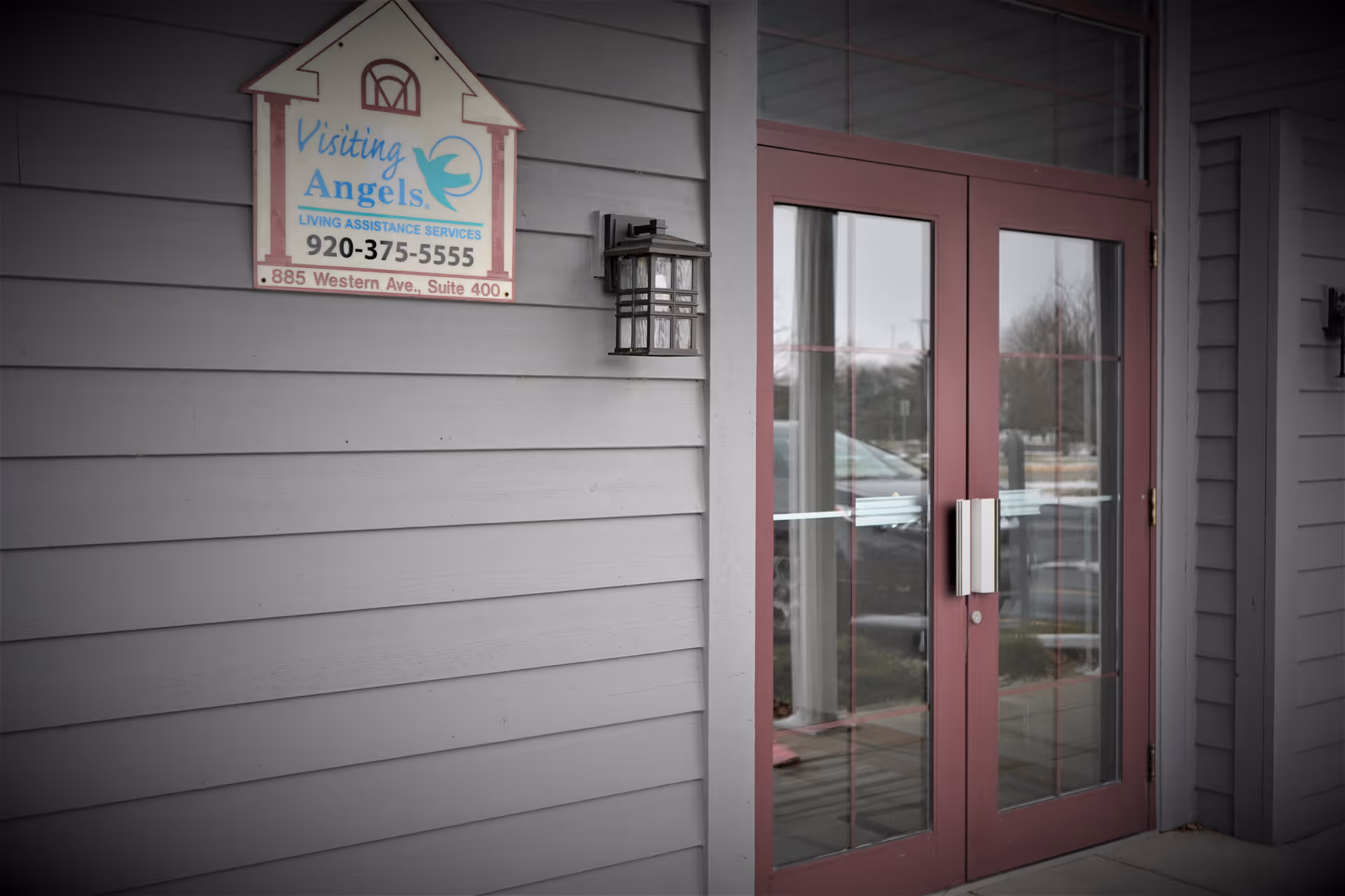 Exterior view of Visiting Angels sign beside a pink-framed glass door.
