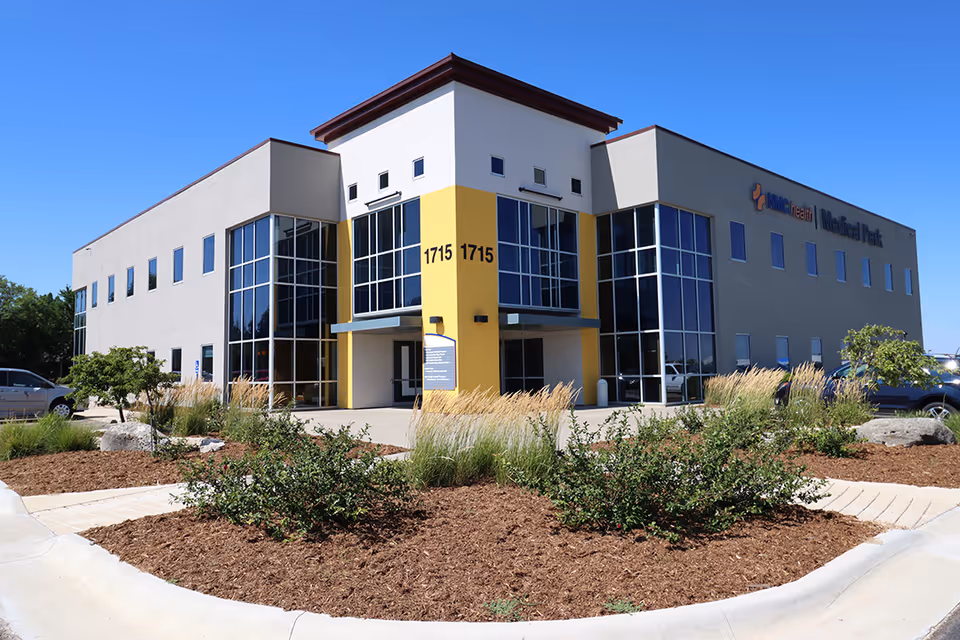Exterior view of a modern senior living facility with yellow entrance and glass façade