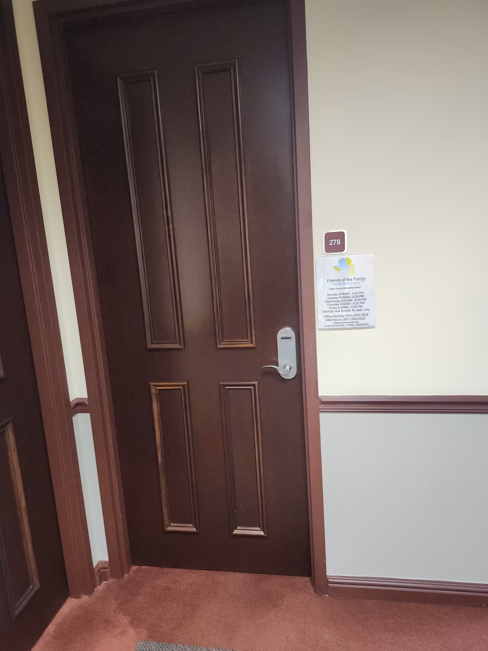 A dark wooden door in a beige hallway with a 278 room sign