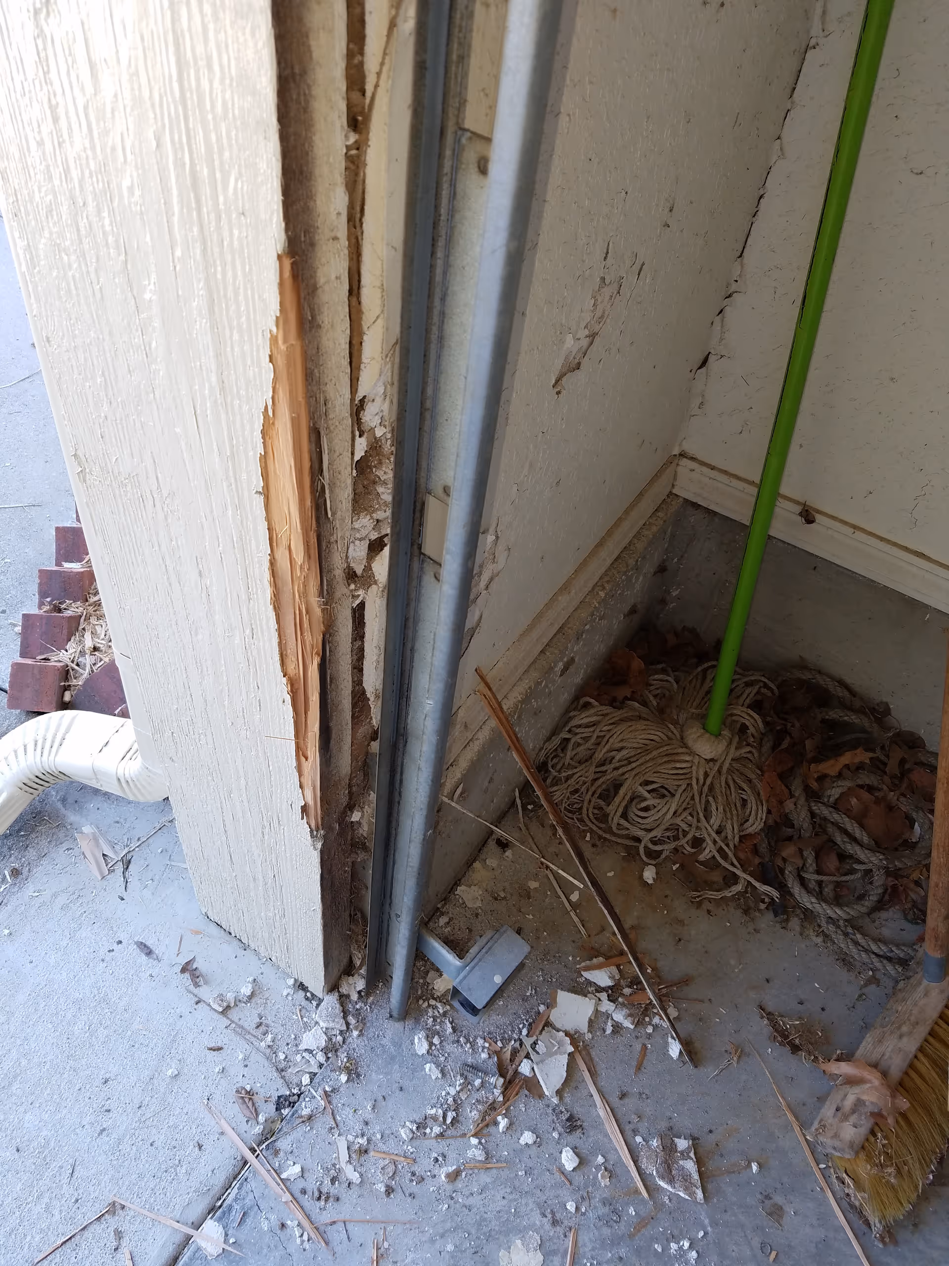 Interior doorway reveals a damaged wall with peeling plaster and debris.