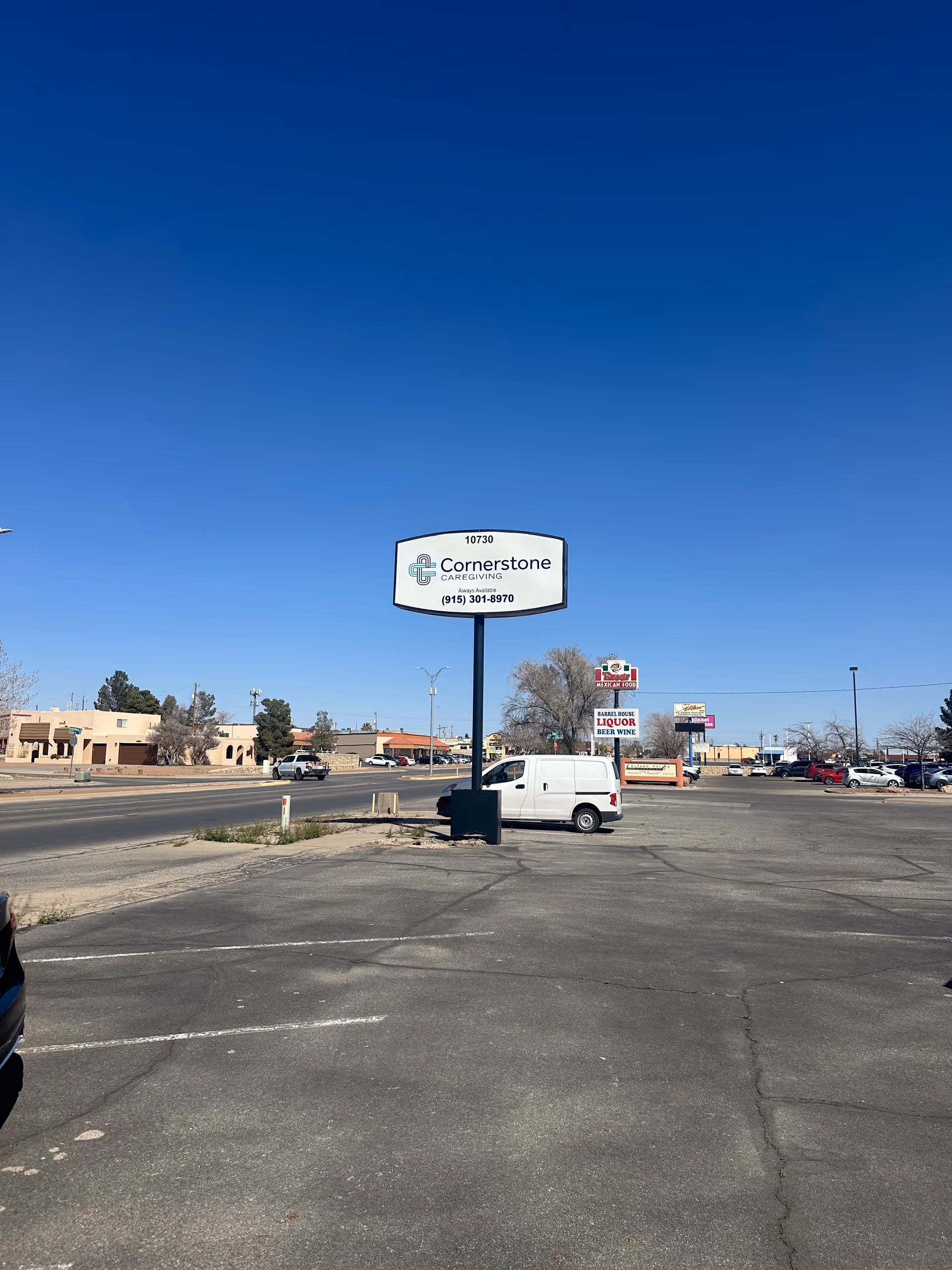 Tall Cornerstone Caregiving sign towers over an empty parking lot and storefronts.