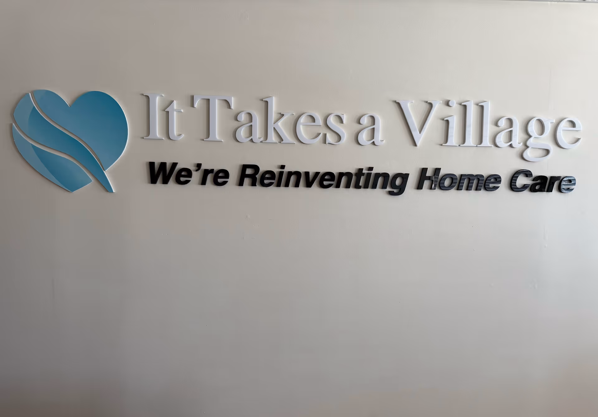 Interior wall featuring It Takes a Village sign and blue heart logo.