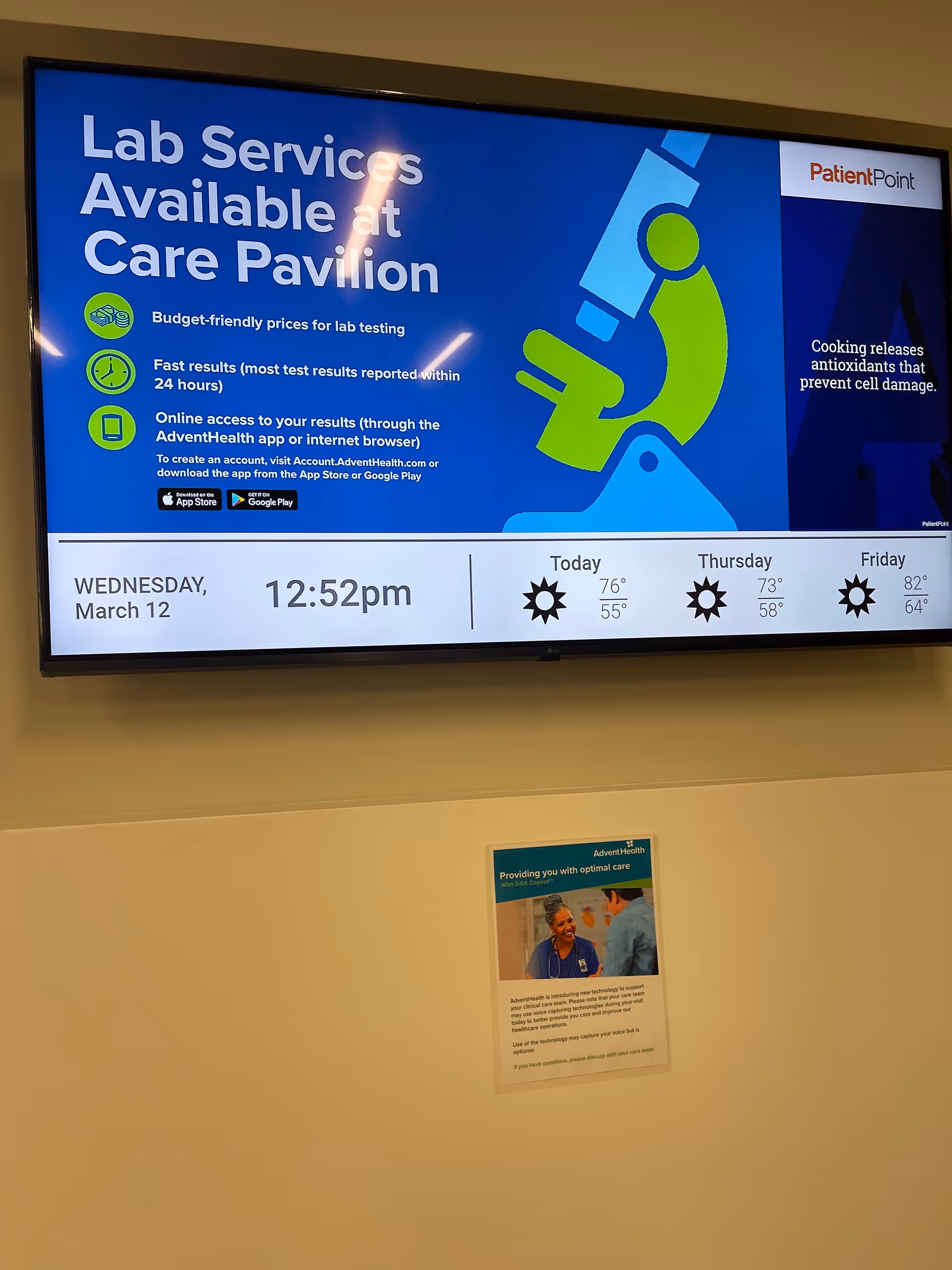 Interior hallway with a large blue digital display advertising lab services.