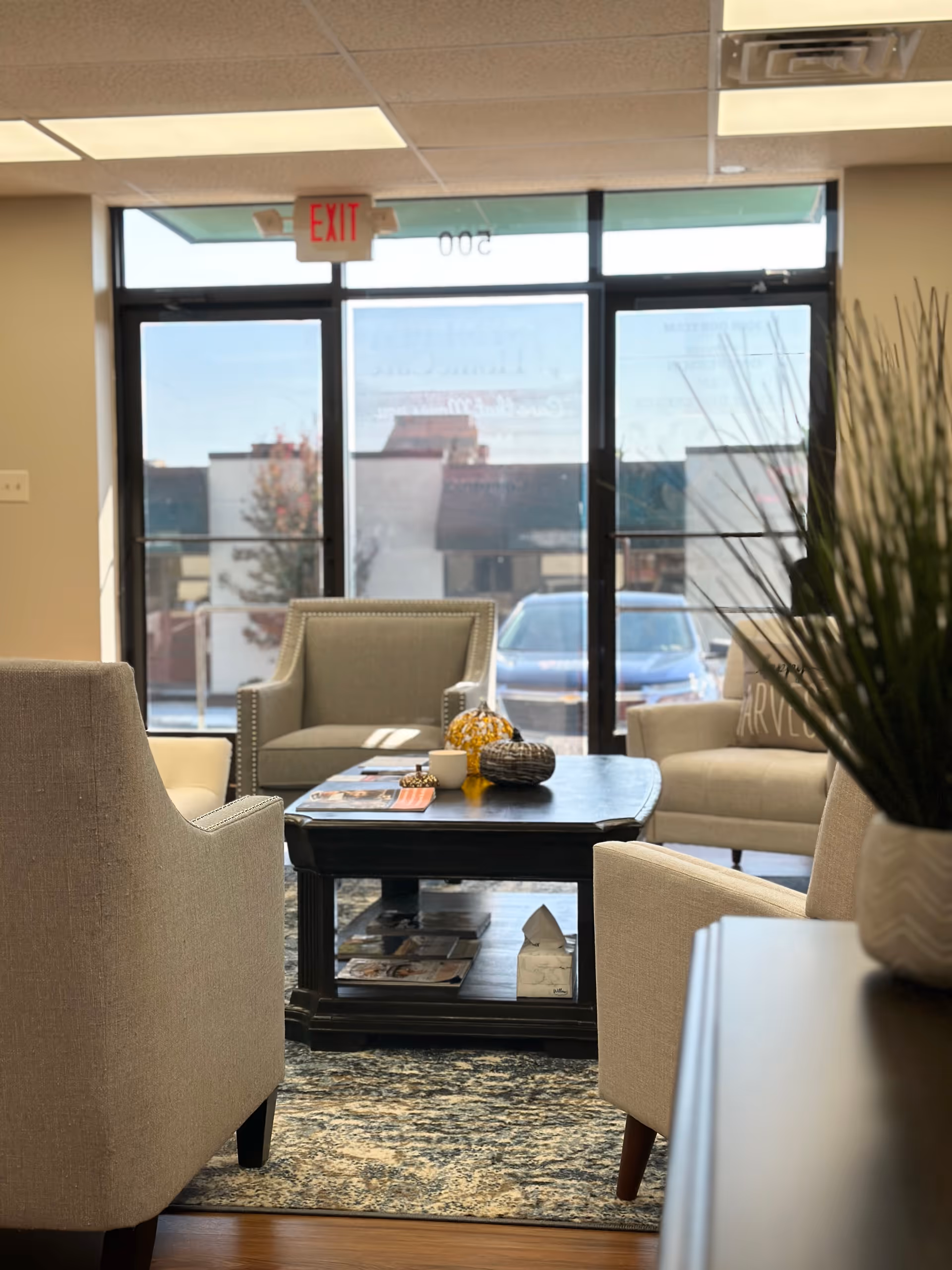 Cozy lobby seating area with beige chairs, coffee table, and large glass doors.
