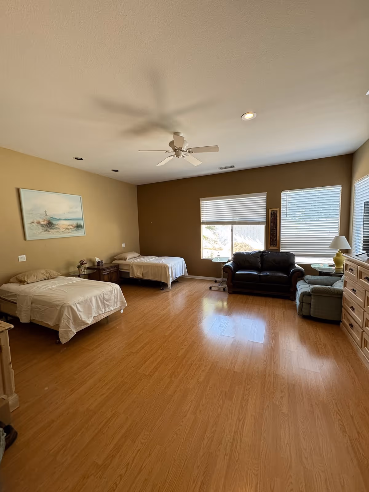 Spacious resident room with two beds, sofa, dresser, and large windows.