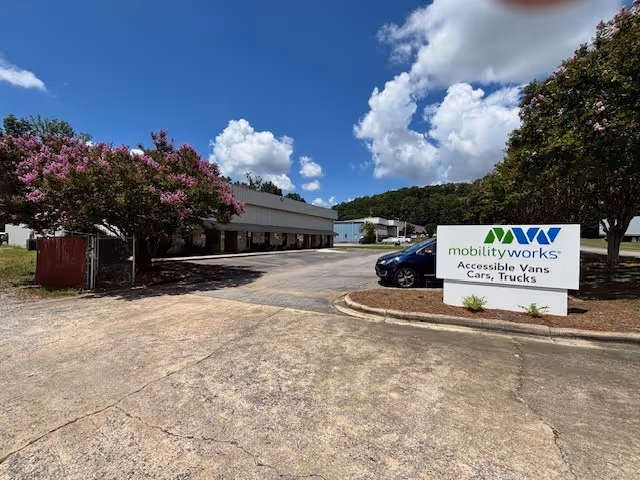 Exterior view of MobilityWorks facility with sign, parking lot, and flowering trees.