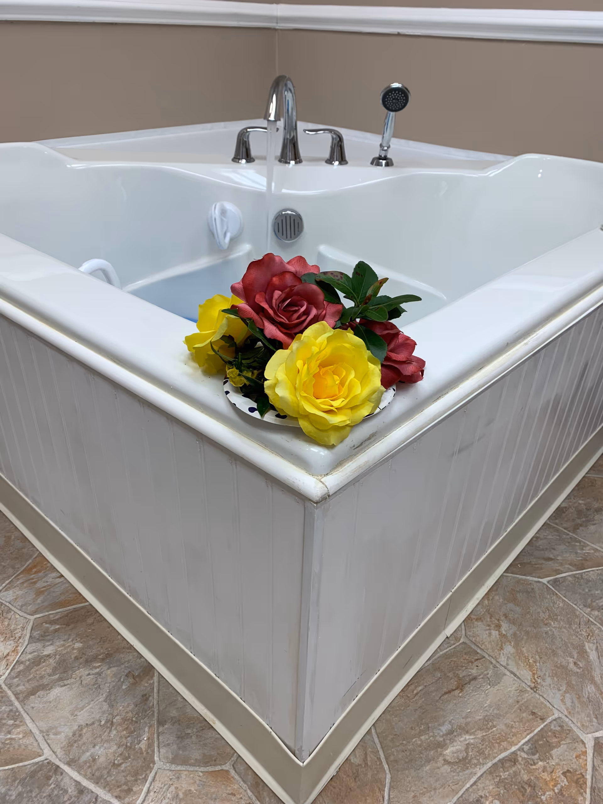 White jetted tub with a colorful bouquet on its edge.