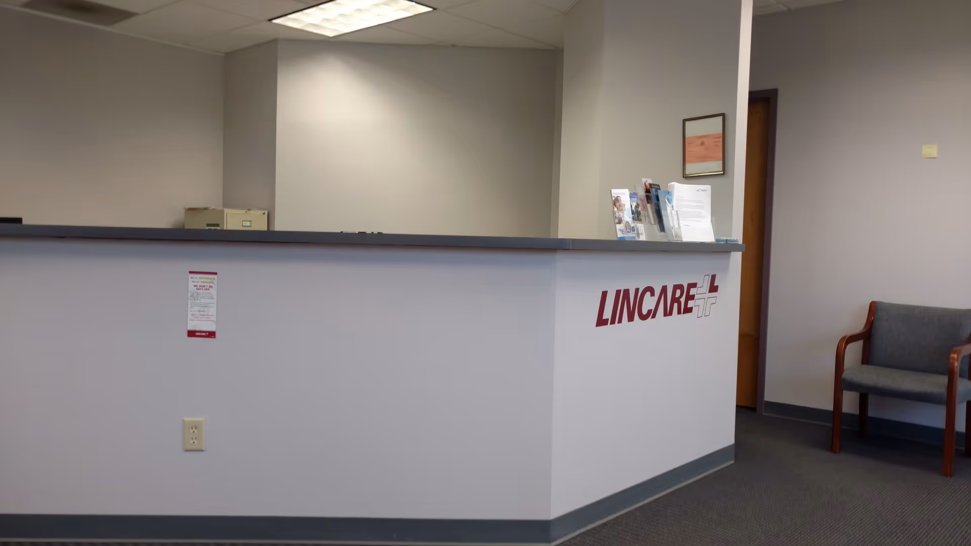 Interior reception desk with LINCARE branding, brochures, and a nearby seating area.