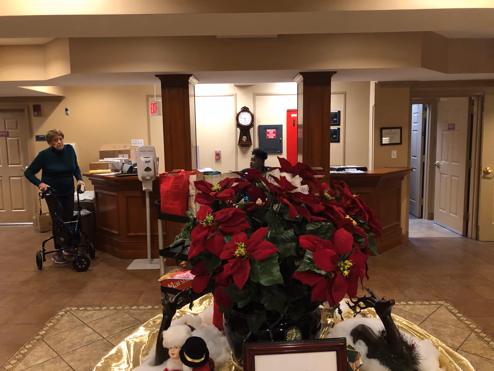 Lobby area with a reception desk, clock, and large red poinsettia centerpiece.