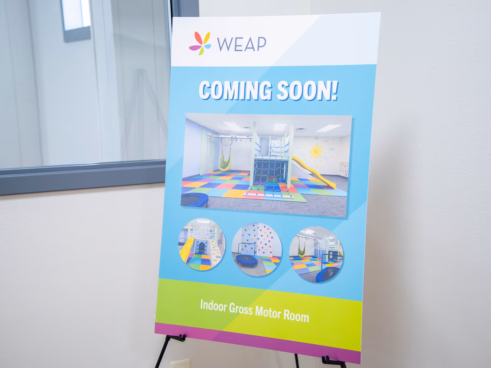 Interior signboard labeled WEAP advertising 'Coming Soon' for Indoor Gross Motor Room.