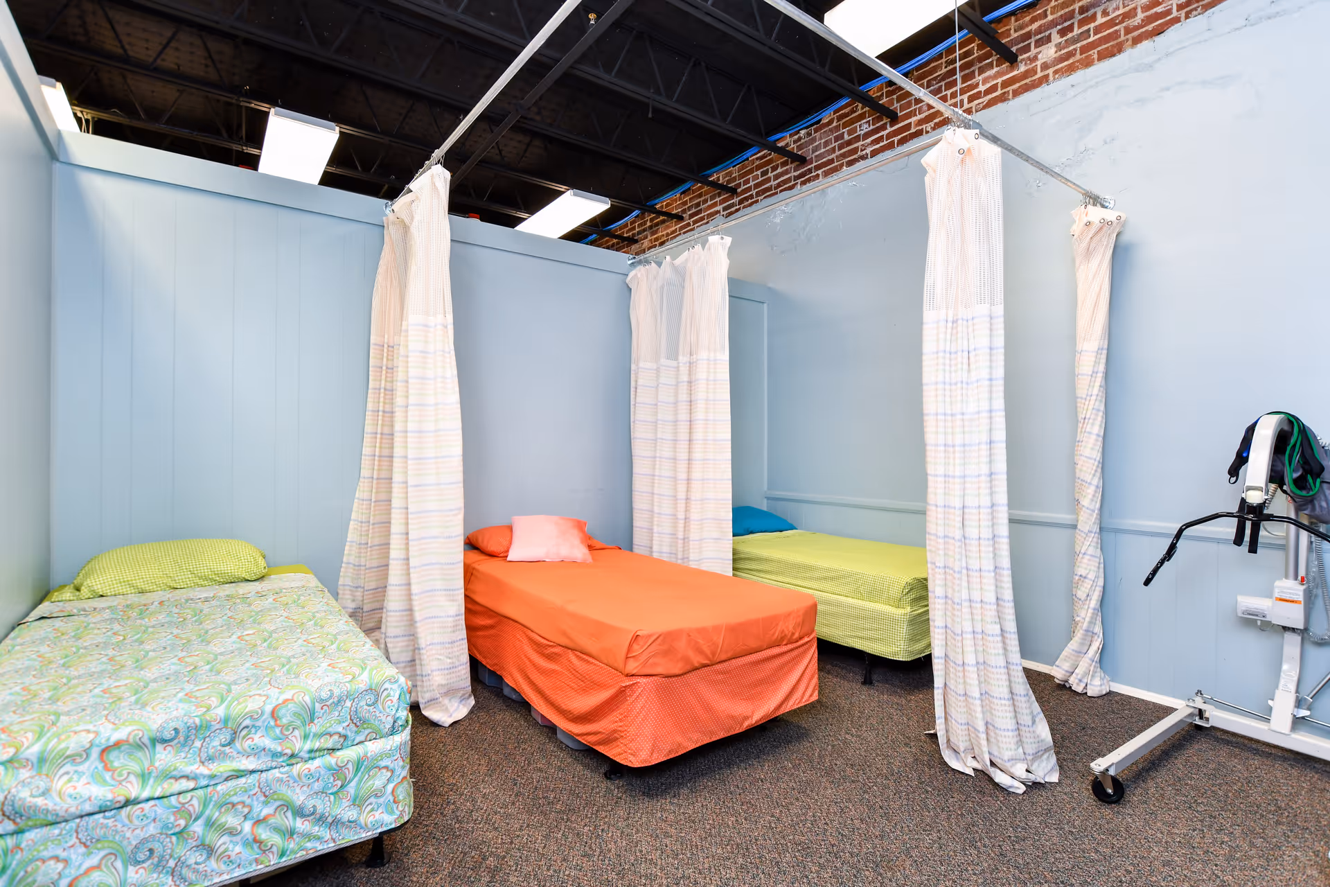 Bright shared bedroom with three beds separated by privacy curtains.