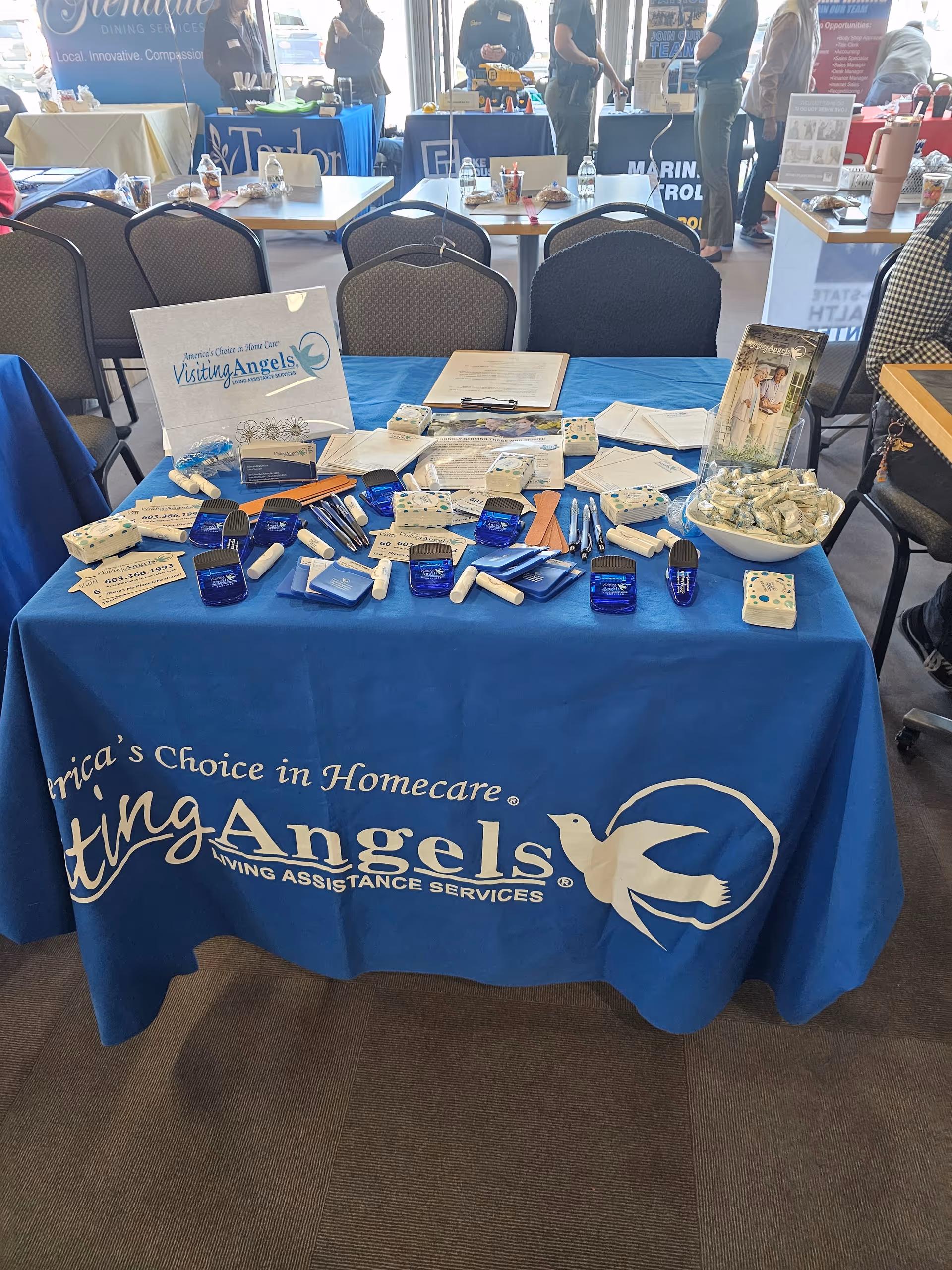 Blue tablecloth booth displaying Visiting Angels materials at a senior care expo.