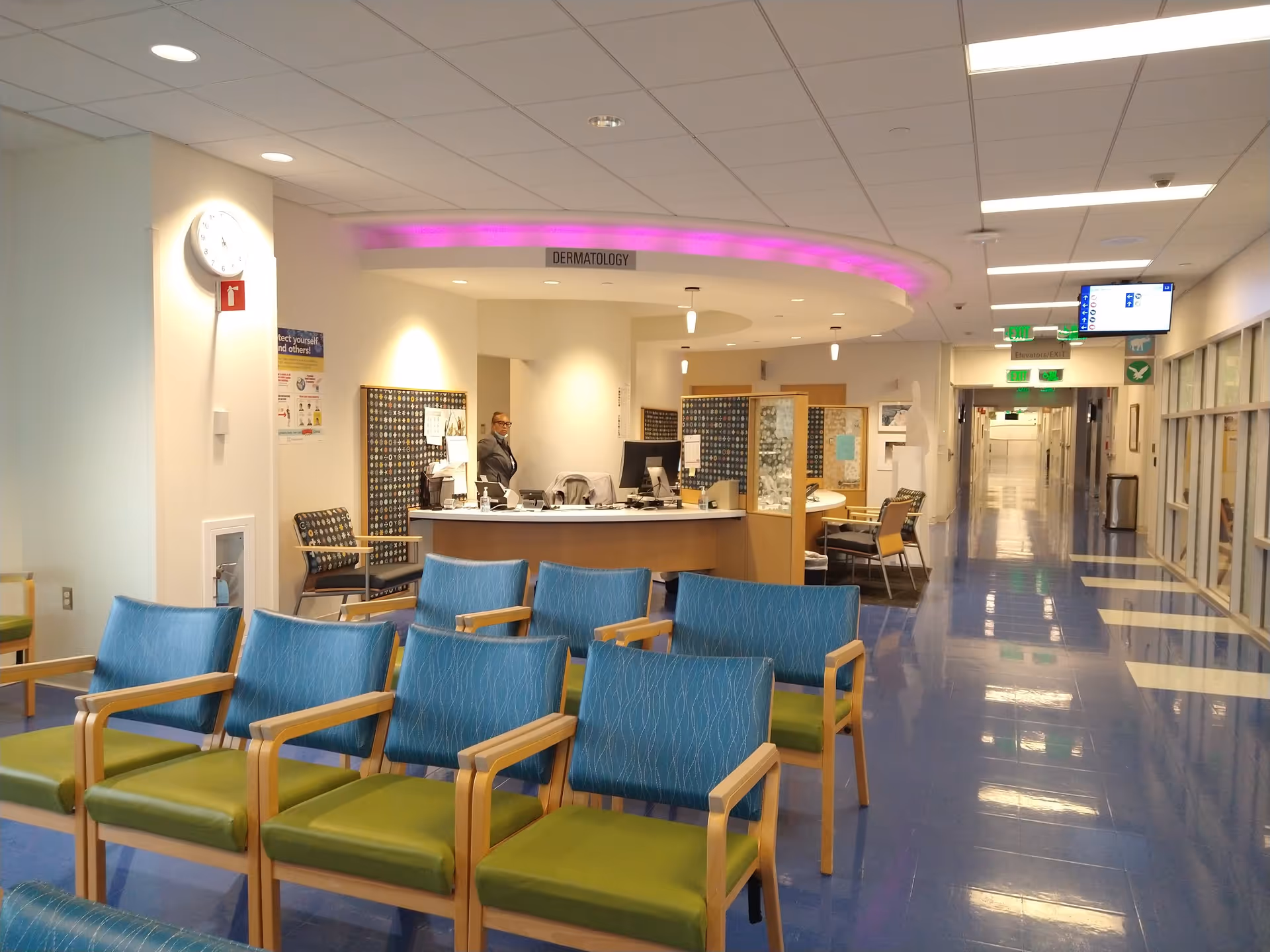 Waiting area with blue chairs and a reception desk in an outpatient medical center.