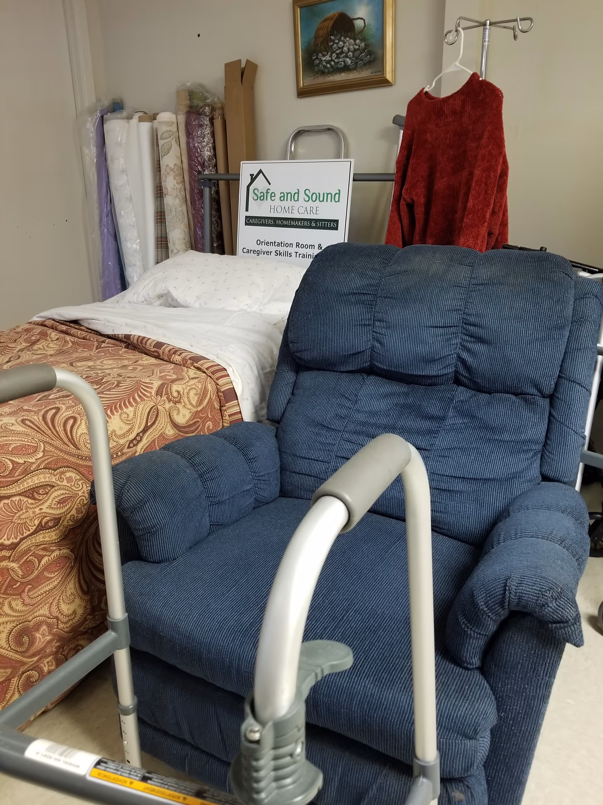 Blue recliner beside a bed in a small bedroom, with walker and Safe and Sound sign.