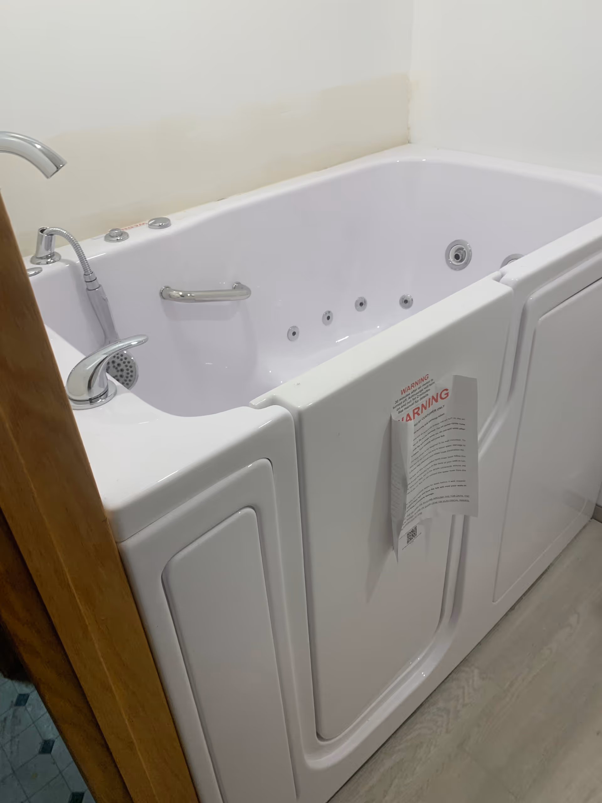 White walk-in tub with jets and safety door in bathroom.