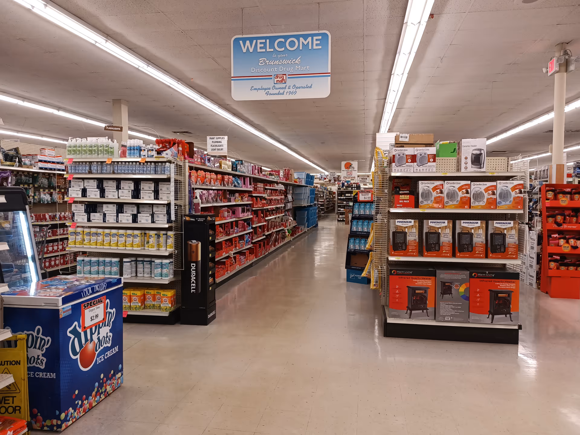 Long interior aisle of a Discount Drug Mart store with shelves of products.