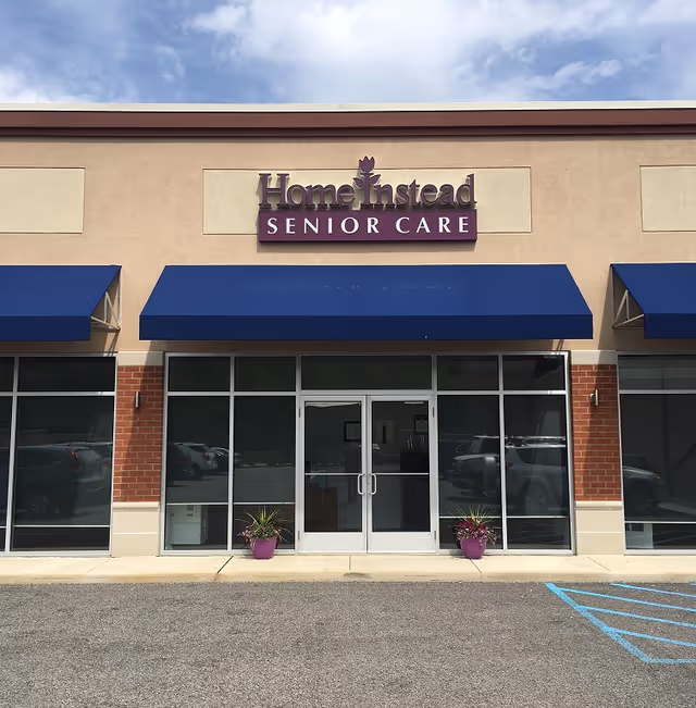 Front exterior of Home Instead Senior Care building with blue awnings and glass doors.