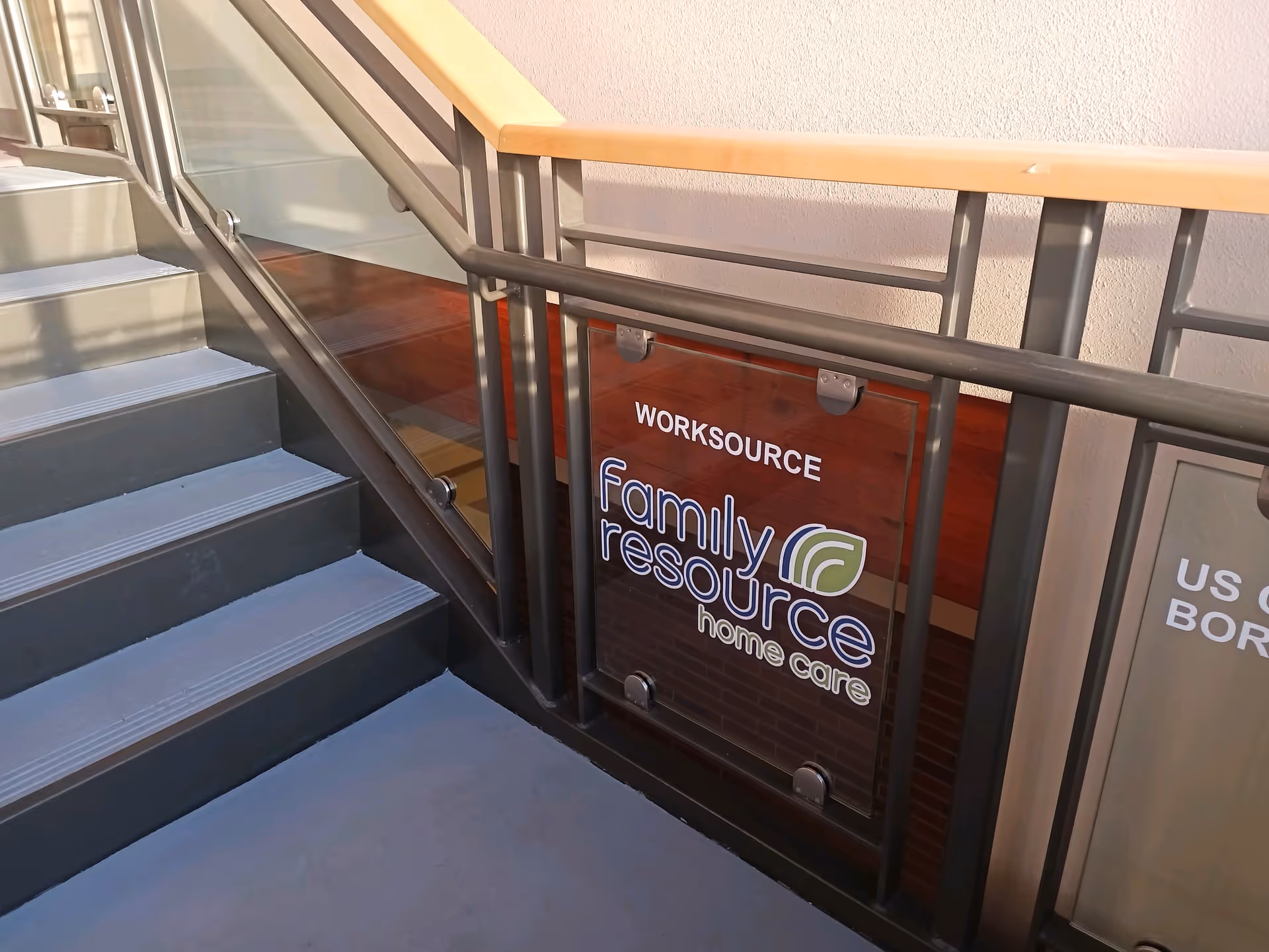 Indoor stairwell with metal railing and a Family Resource Home Care sign.