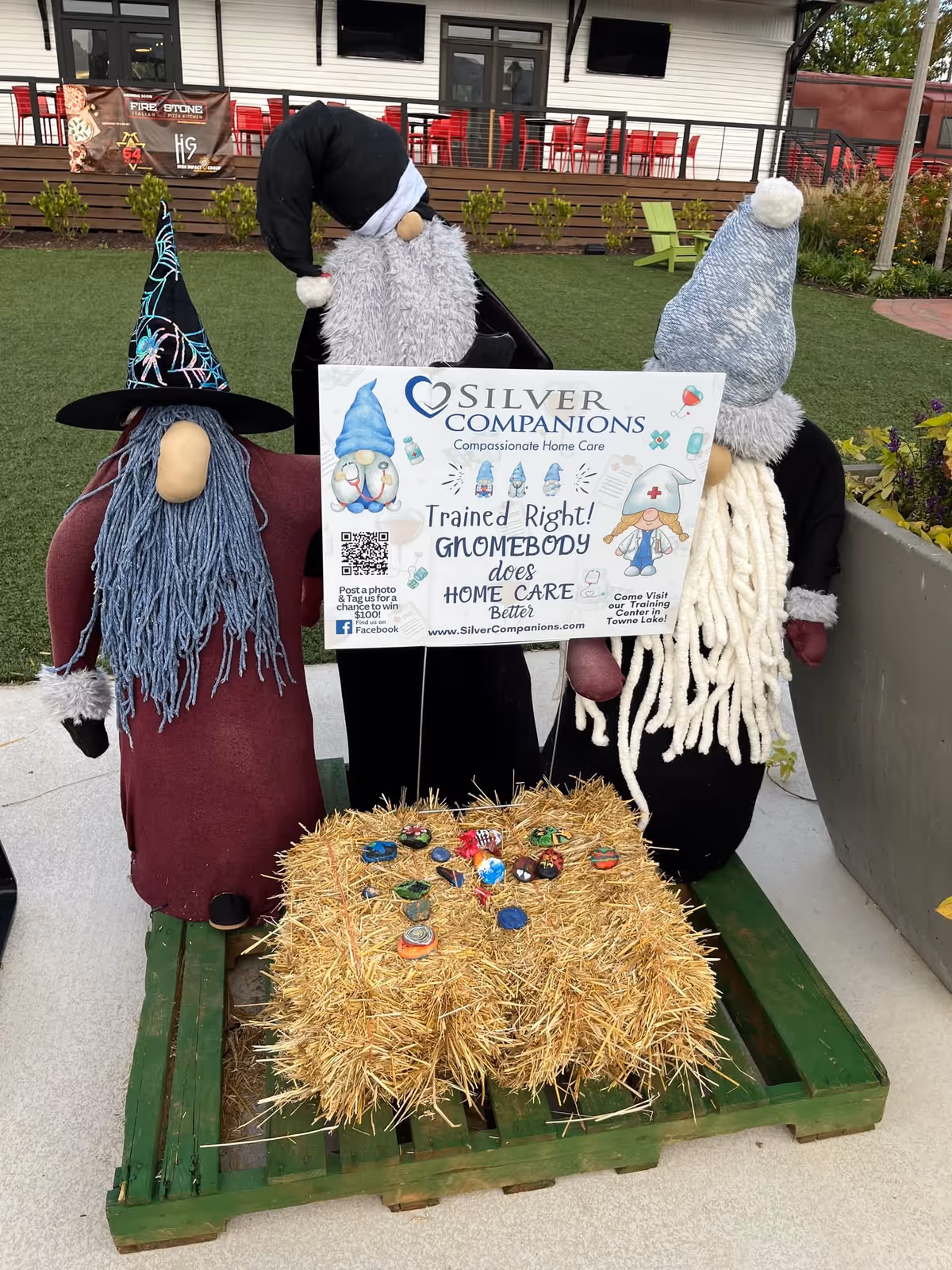 Outdoor patio display featuring large gnome figures, a hay bale, and a Silver Companions sign.
