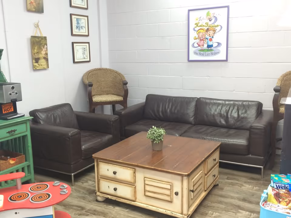 Cozy lounge with brown leather sofas around a coffee table and wicker chairs, with wall art.