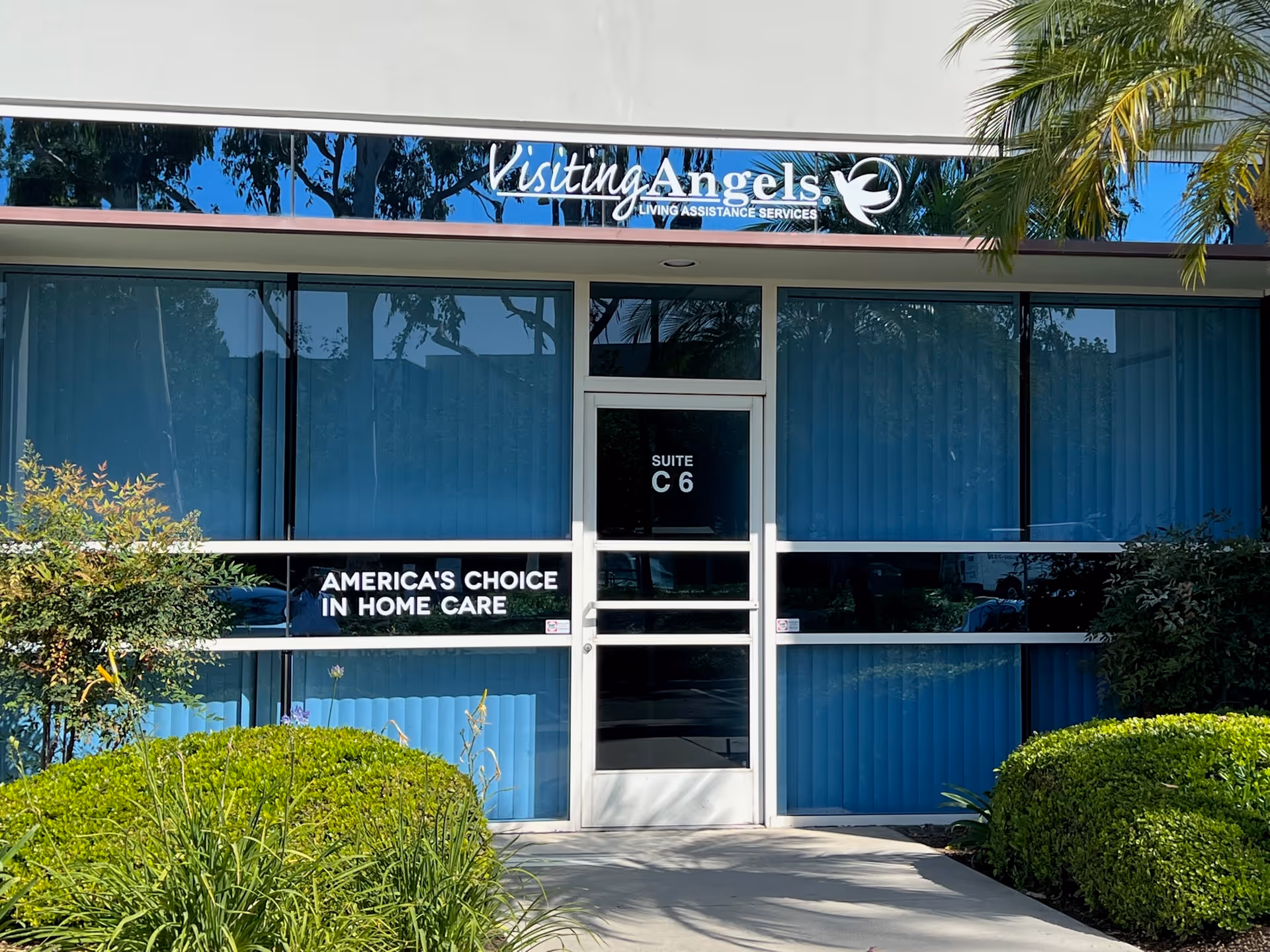 Front view of Visiting Angels Senior Home Care storefront with glass doors and blue window blinds.