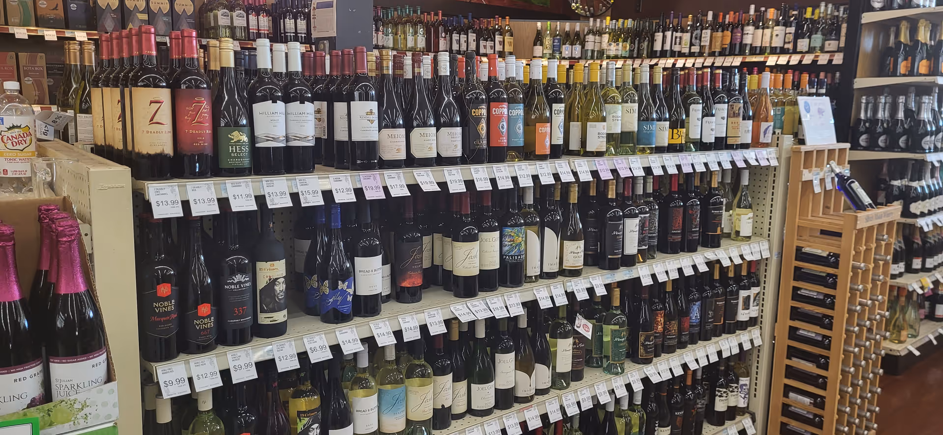 Aisle with numerous wine bottles lined on shelves inside a Discount Drug Mart.