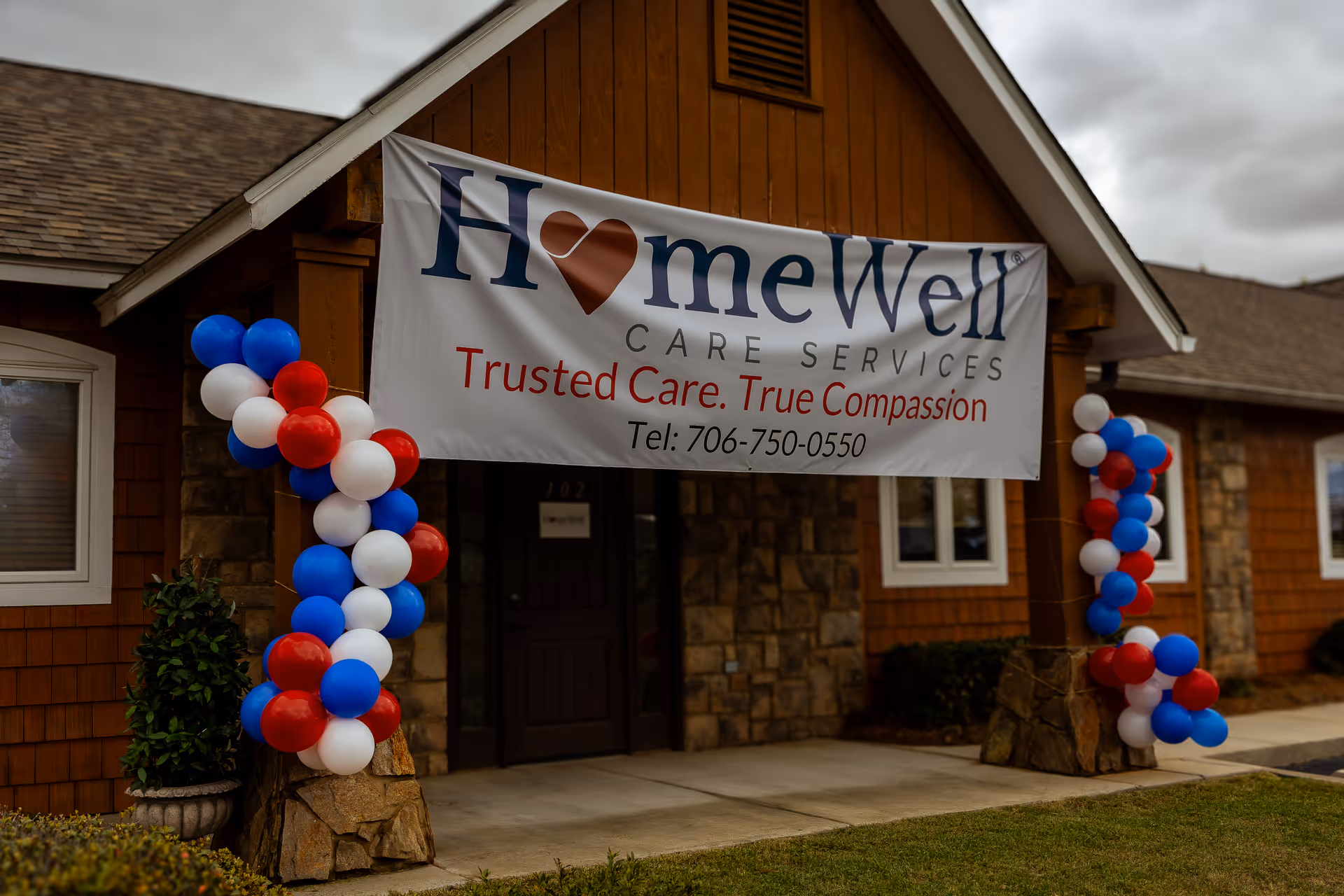 Exterior view of HomeWell Care Services building with balloon-decorated entrance and banner