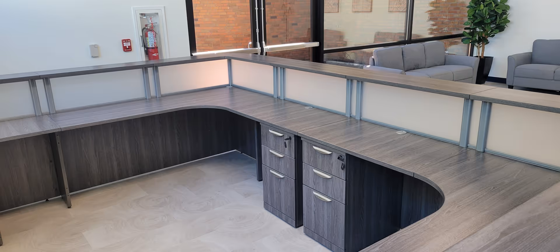 A modern curved front desk in a lobby with couches and large windows.
