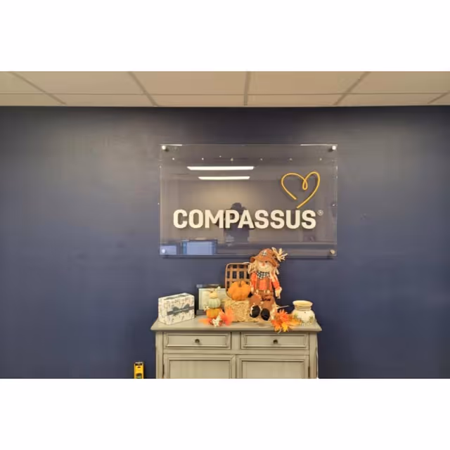 Indoor blue wall features Compassus sign with autumn decorations atop a cabinet.